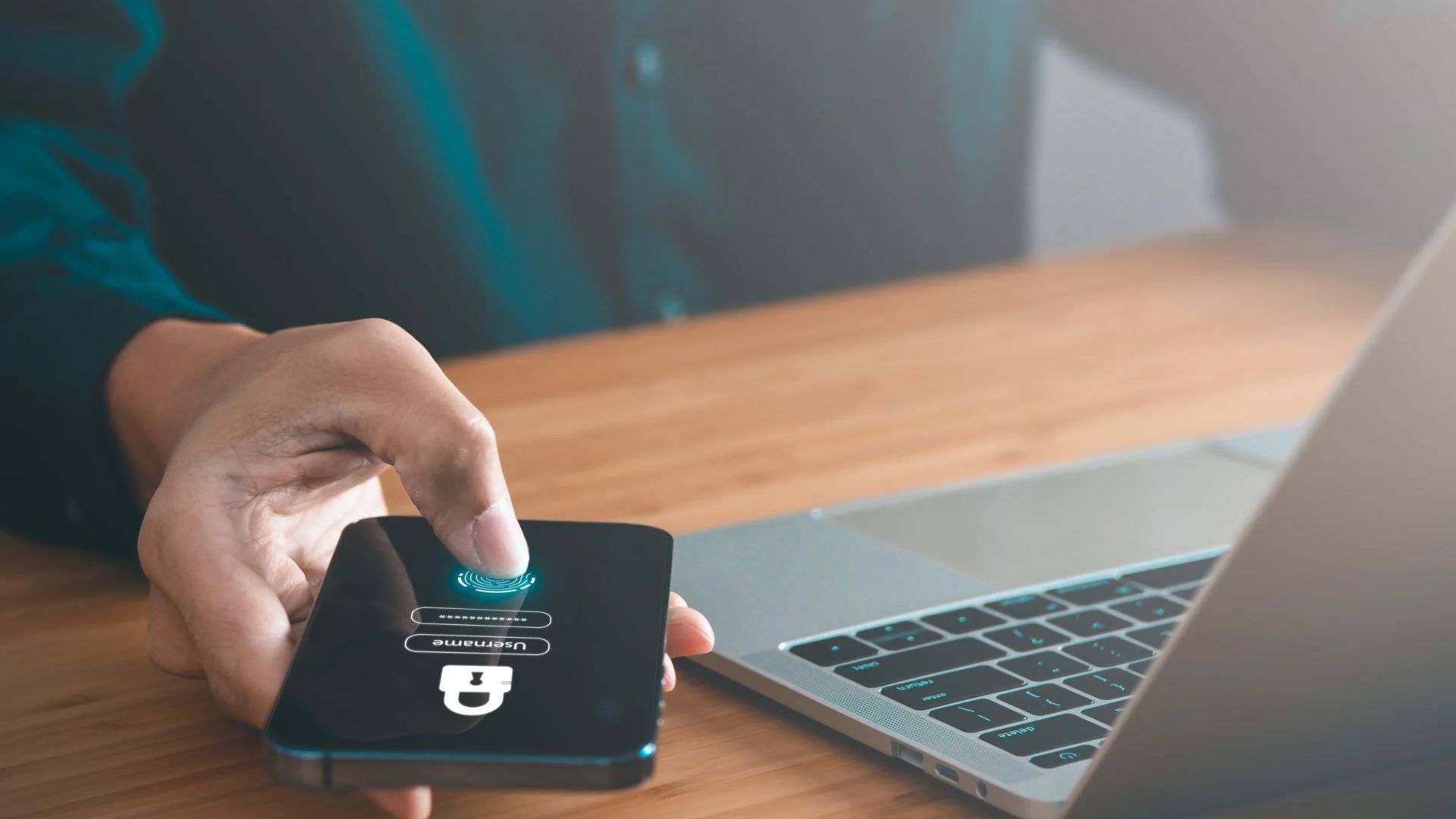 Collaboratore conferma con l’impronta digitale sullo smartphone un accesso con autenticazione a più fattori, accanto al portatile